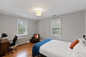 a bedroom with a bed and a desk and two windows at Stately 5BR Historic Retreat CozySuites in Alexandria
