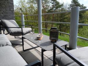 un patio con 2 sillas y una mesa con copas de vino en Apartment Château Castelnau on a golf course in Durbuy, en Barvaux