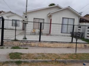 una cerca frente a una casa blanca en Cabañas Herradura Oriente, en Coquimbo