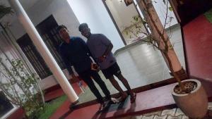 Zwei Männer stehen vor einem Haus. in der Unterkunft Hotel white house mahiyanganaya in Mahiyangana