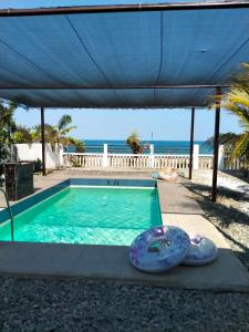 a swimming pool with an awning and the ocean at Cesar Villa sea side in Tagudin