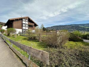 une maison sur une colline avec une clôture et des buissons dans l'établissement Landhaus Eibele, à Oberstaufen