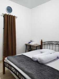 una camera da letto con un letto con un orologio sul muro di HAPDESKO HOMESTAY a Batam Center