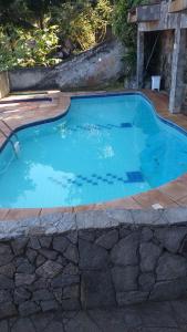 una piscina de agua azul en un patio en ESCAPE PARA O PARAISO, Casa Mobiliada com PISCINA e Salão de jogos, 300mt da PRAIA en Arraial do Cabo