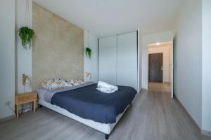 - une chambre dotée d'un grand lit avec des draps bleus dans l'établissement Le Havre de Sérénité - Orly - Gare - Place privée, à Athis-Mons