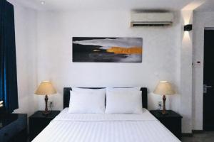 1 dormitorio con 1 cama con sábanas blancas y 2 lámparas en Journey Sai Gon Bui Vien Walking Street en Ho Chi Minh