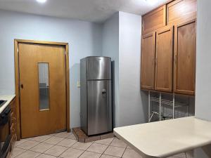a kitchen with a stainless steel refrigerator and wooden cabinets at Casa Valentina in Sayula