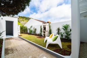 um jardim com uma casa branca e uma cadeira branca em Casa Cecilia Meireles em Ponta Delgada