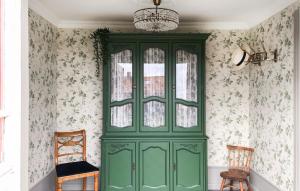 a green cabinet in a room with floral wallpaper at 2 Bedroom Awesome Home In Degerhamn in Degerhamn