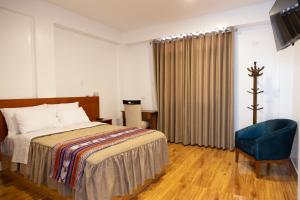 豪哈的住宿－Zavala Hotels & Resorts，一间卧室配有一张床和一张蓝色椅子