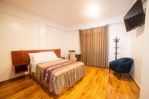 豪哈的住宿－Zavala Hotels & Resorts，一间卧室配有一张床、一台电视和一把椅子