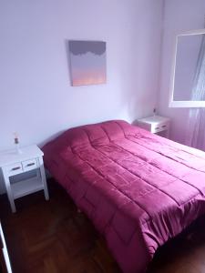 um quarto com uma cama rosa e uma mesa em HOSPEDAJE DEL PARQUE- Zona centro de Monte Grande-15 min del Aeropuerto de EZE!! ESTACIONAMIENTO GRATIS! em Monte Grande