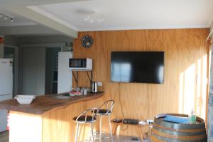 uma cozinha com um bar com uma televisão na parede em Jacks place em Moeraki