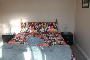 a bedroom with a bed with a flowered bedspread at Jacks place in Moeraki