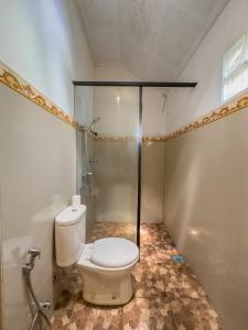 a bathroom with a toilet and a shower at Mulia Garden Bungalows in Tabanan