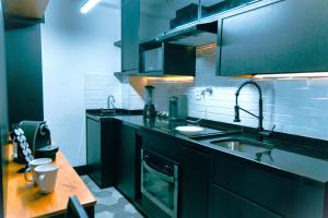 a kitchen with black cabinets and a sink at Studio a 100m Bosque, Centro e Cambuí- Home Office, Piscina, Sauna, Jacuzzi, Fitness in Campinas