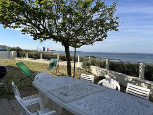 un tavolo bianco con sedie, un albero e l'oceano di Maison de 5 pièces avec jardin clos et vue sur mer à l'Herbaudière - FR-1-224B-223 a Noirmoutier-en-l'lle