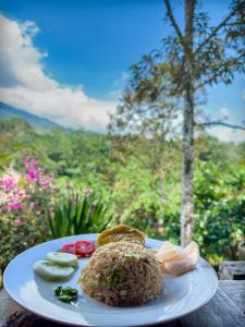 a plate of food with rice and vegetables on a table at Mulia Garden Bungalows in Tabanan
