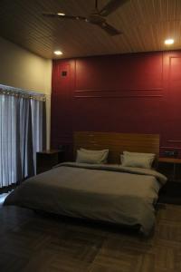 1 dormitorio con 1 cama grande y pared roja en Maakot en Nainital