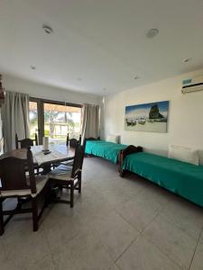1 dormitorio con camas verdes, mesa y sillas en Chajari Suites en Chajarí