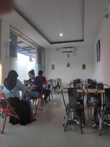 a group of people sitting at tables in a room at The Galton Hotel in Baubau