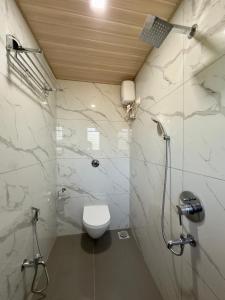 a bathroom with a white toilet and a shower at Sapphire Mansion in Alibag