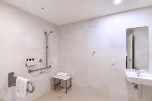 a white bathroom with a sink and a shower at Kith Hotel Darling Harbour in Sydney