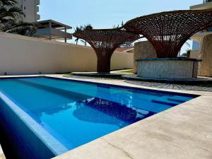 una piscina con 2 sombrillas junto a un edificio en Vista al mar, Alberca, Netflix, Playa - Facturamos, en Conchal