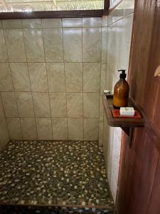 River Point Hostel في بويرتو مالدونادو: حمام مع دش وزجاجة على الرف