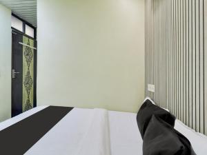 - une chambre avec un lit blanc et des oreillers noirs dans l'établissement OYO Hotel Metro View, à Mumbai