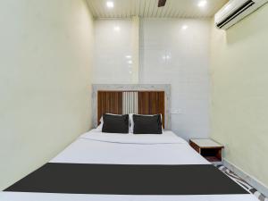 - une chambre avec un lit blanc et des oreillers noirs dans l'établissement OYO Hotel Metro View, à Mumbai