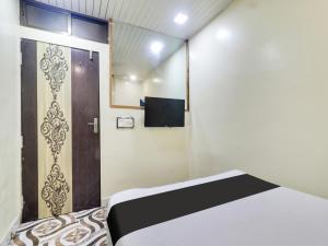 Cette chambre dispose d'un lit et d'une porte avec une télévision. dans l'établissement OYO Hotel Metro View, à Mumbai