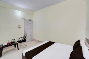 PrayagrajにあるOYO Flagship Hotel Suryaのベッドルーム1室(ベッド1台、テーブル、椅子付)