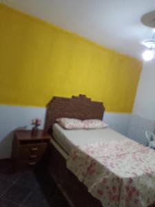 1 dormitorio con cama y pared amarilla en Pousada Villa do Mar, en Itaparica
