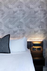 a bedroom with a white bed and a patterned wall at Kith Hotel Darling Harbour in Sydney
