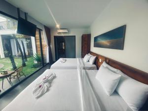 Habitación de hotel con 2 camas con sábanas blancas en Tuong Vy Boutique Hotel Mui Ne en Mui Ne