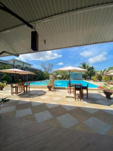 un patio con mesas y sombrillas junto a una piscina en Buona Vita resort, en Panglao