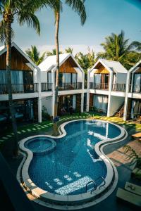 una piscina frente a un complejo con palmeras en Tuong Vy Boutique Hotel Mui Ne en Mui Ne