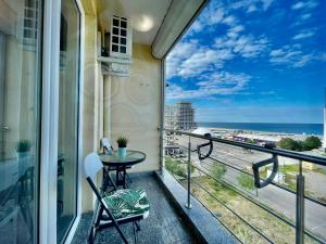 balcón con mesa, sillas y vistas al océano en Nico Summer Apartment, en Mamaia