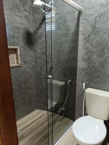 a bathroom with a toilet and a glass shower at Chalé Rj Rio in Santo Amaro