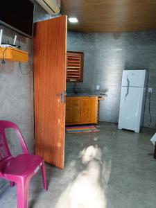a dog in a kitchen with a pink chair and a refrigerator at Chalé Rj Rio in Santo Amaro