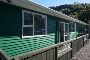 a green house with a window and a fence at The Green Guesthouse - beautiful semi rural family unit in Lower Hutt