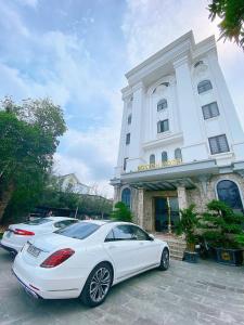 two white cars parked in front of a building at Boston Halong Hotel in Ha Long