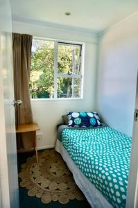 Habitación pequeña con cama y ventana en The Green Guesthouse - beautiful semi rural family unit, en Lower Hutt