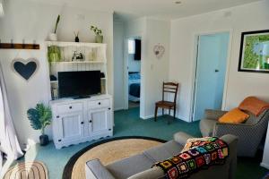 sala de estar con sofá y TV de pantalla plana en The Green Guesthouse - beautiful semi rural family unit, en Lower Hutt