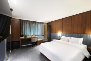 仁川にあるBrowndot Incheon Airport New Cityの大きなベッドとデスクが備わるホテルルームです。
