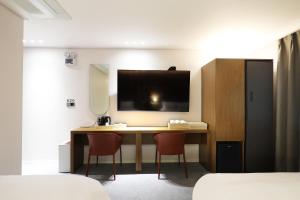仁川的住宿－Browndot Incheon Airport New City，一间卧室配有一张桌子、两把椅子和一台电视
