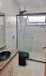 uma casa de banho com um WC e uma cabina de duche em vidro. em Locação Temporada Cabo Frio RJ. em Cabo Frio
