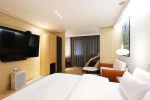 仁川にあるBrowndot Incheon Airport New Cityのベッド1台、薄型テレビが備わるホテルルームです。