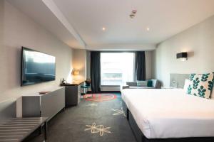 オークランドにあるSkyCity Hotel Aucklandの大型ベッド1台、薄型テレビが備わるホテルルームです。